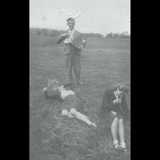 an acordeonist and two girls in a field in the 50s