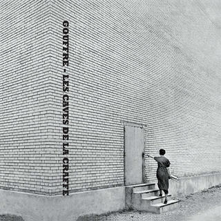 a b&w big wall and a girl opening a door
